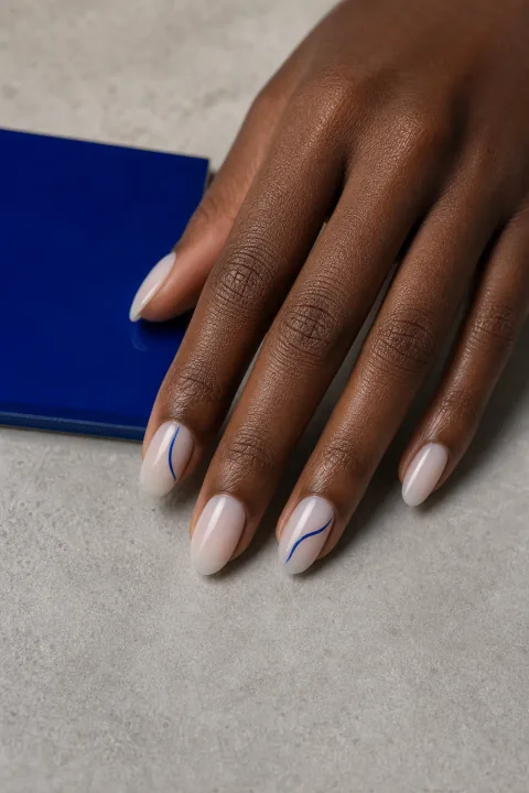 Mão com unhas amendoadas leitosas e linhas curvas azuis em duas unhas